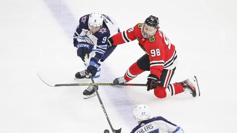 Feb 23, 2024; Chicago, Illinois, USA; Winnipeg Jets left wing Alex Iafallo (9) battles for the puck with Chicago Blackhawks center Connor Bedard (98) during the first period at United Center. Mandatory Credit: Kamil Krzaczynski-USA TODAY Sports