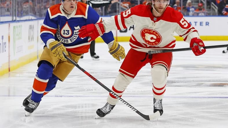 Feb 24, 2024; Edmonton, Alberta, CAN; Calgary Flames defensemen Noah Hanifin (55) and Edmonton Oilers forward Mattias Janmark (13) chase a loose puck during the first period at Rogers Place. Mandatory Credit: Perry Nelson-USA TODAY Sports
