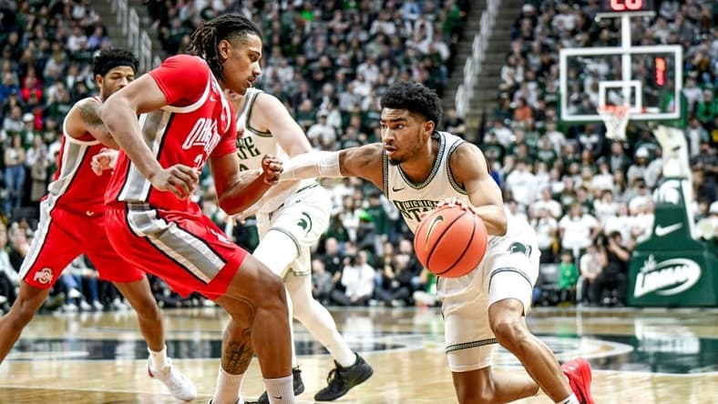 Michigan State's Jaden Akins, right, moves the ball as Ohio State's Devin Royal defends during the first half on Sunday, Feb. 25, 2024, at the Breslin Center in East Lansing.