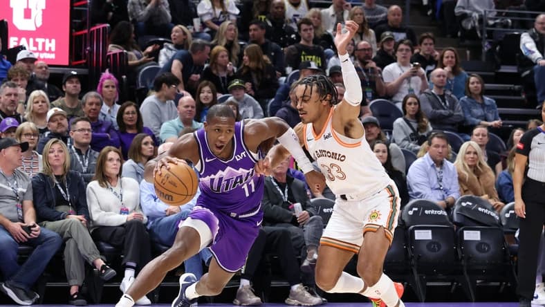 Feb 25, 2024; Salt Lake City, Utah, USA; Utah Jazz guard Kris Dunn (11) drives against San Antonio Spurs guard Tre Jones (33) during the second quarter at Delta Center. Mandatory Credit: Rob Gray-USA TODAY Sports