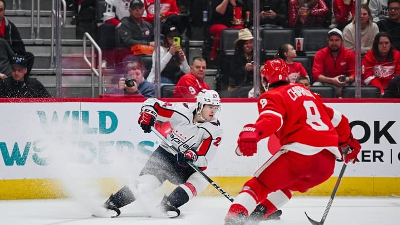 Feb 27, 2024; Detroit, Michigan, USA; Washington Capitals center Connor McMichael (24) brings the puck up ice against Detroit Red Wings defenseman Ben Chiarot (8) during the first period at Little Caesars Arena. Mandatory Credit: Tim Fuller-USA TODAY Sports