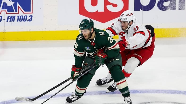 Feb 27, 2024; Saint Paul, Minnesota, USA; Minnesota Wild right wing Ryan Hartman (38) skates with the pucka as Carolina Hurricanes defenseman Brett Pesce (22) defends during the third period at Xcel Energy Center. Mandatory Credit: Matt Krohn-USA TODAY Sports