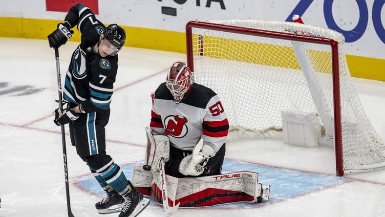 Feb 27, 2024; San Jose, California, USA;  New Jersey Devils goaltender Nico Daws (50) makes a save as San Jose Sharks center Nico Sturm (7) tries to deflect the puck into the net during the third period at SAP Center at San Jose. Mandatory Credit: Neville E. Guard-USA TODAY Sports