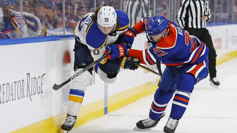 Feb 28, 2024; Edmonton, Alberta, CAN; St. Louis Blues forward Oskar Sundqvist (70) and Edmonton Oilers defensemen Brett Kulak (27)  battle for a loose puck  during the second period at Rogers Place. Mandatory Credit: Perry Nelson-USA TODAY Sports