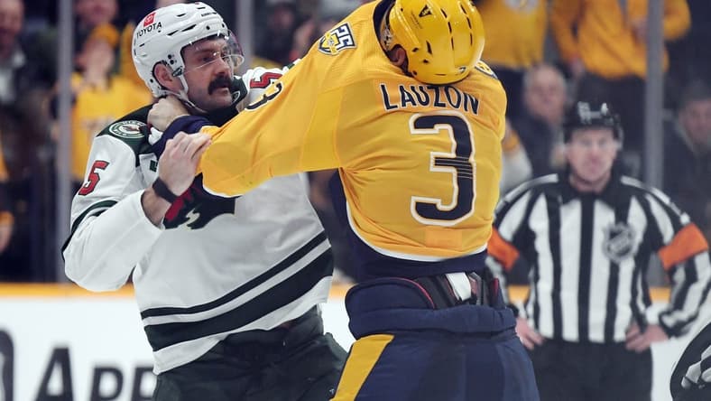 Feb 29, 2024; Nashville, Tennessee, USA; Minnesota Wild defenseman Jake Middleton (5) and Nashville Predators defenseman Jeremy Lauzon (3) exchange punches during a fight during the second period at Bridgestone Arena. Mandatory Credit: Christopher Hanewinckel-USA TODAY Sports