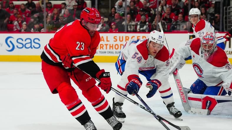 Dec 28, 2023; Raleigh, North Carolina, USA; Carolina Hurricanes right wing Stefan Noesen (23) ties to get his shot by Montreal Canadiens defenseman Jordan Harris (54) during the third period at PNC Arena. Mandatory Credit: James Guillory-USA TODAY Sports