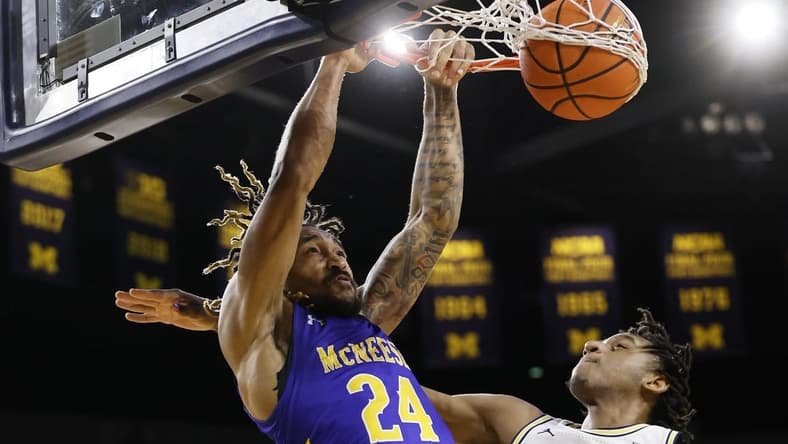 Dec 29, 2023; Ann Arbor, Michigan, USA; McNeese State Cowboys forward Christian Shumate (24) dunks on Michigan Wolverines forward Tarris Reed Jr. (32) in the second half at Crisler Center. Mandatory Credit: Rick Osentoski-USA TODAY Sports