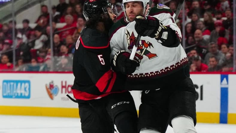 Jan 27, 2024; Raleigh, North Carolina, USA; Arizona Coyotes left wing Jason Zucker (16) checks Carolina Hurricanes defenseman Jalen Chatfield (5) during the first period at PNC Arena. Mandatory Credit: James Guillory-USA TODAY Sports