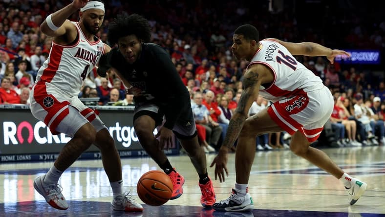 Feb 24, 2024; Tucson, Arizona, USA; Washington Huskies guard Sahvir Wheeler (5) drives to the net against Arizona Wildcats guard Kylan Boswell (4) and forward Keshad Johnson (16) during the first half at McKale Center. Mandatory Credit: Zachary BonDurant-USA TODAY Sports