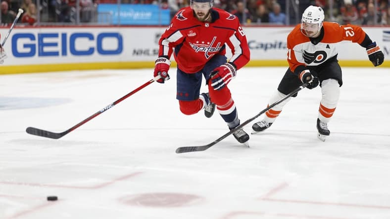 Mar 1, 2024; Washington, District of Columbia, USA; Washington Capitals defenseman Joel Edmundson (6) and Philadelphia Flyers center Scott Laughton (21) chase the puck in the second period at Capital One Arena. Mandatory Credit: Geoff Burke-USA TODAY Sports
