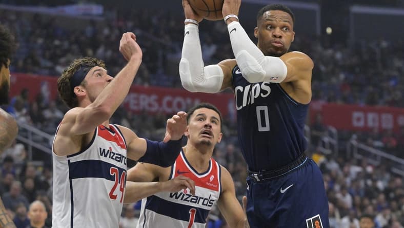 Mar 1, 2024; Los Angeles, California, USA; Los Angeles Clippers guard Russell Westbrook (0) passes the ball as he is defended by Washington Wizards forward Corey Kispert (24) and guard Johnny Davis (1) in the first half at Crypto.com Arena. Mandatory Credit: Jayne Kamin-Oncea-USA TODAY Sports