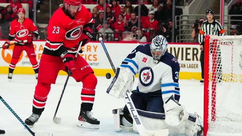 Mar 2, 2024; Raleigh, North Carolina, USA; Winnipeg Jets goaltender Connor Hellebuyck (37) makes a save in front of Carolina Hurricanes right wing Stefan Noesen (23) during the first period at PNC Arena. Mandatory Credit: James Guillory-USA TODAY Sports