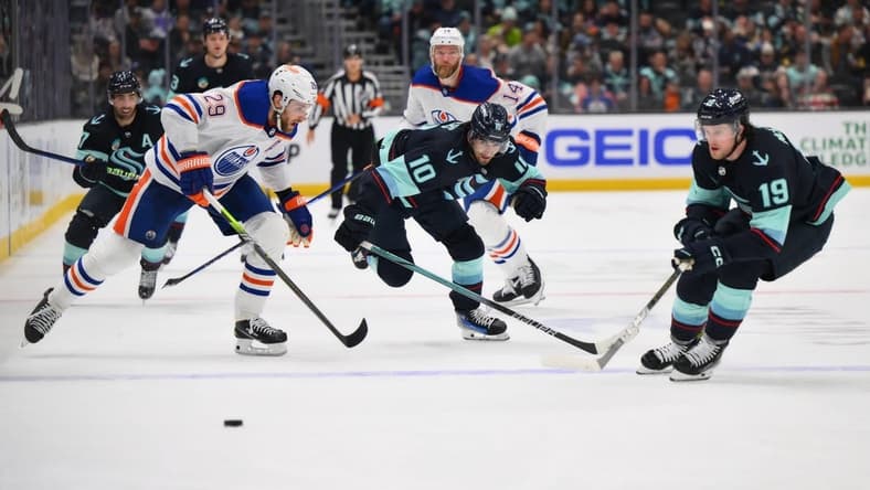 Mar 2, 2024; Seattle, Washington, USA; Edmonton Oilers center Leon Draisaitl (29) and Seattle Kraken center Matty Beniers (10) and left wing Jared McCann (19) chase the puck during the second period at Climate Pledge Arena. Mandatory Credit: Steven Bisig-USA TODAY Sports