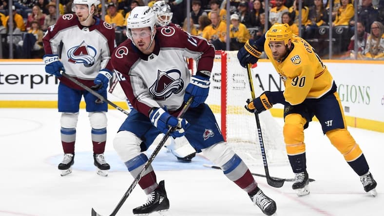 Mar 2, 2024; Nashville, Tennessee, USA; Colorado Avalanche center Ryan Johansen (12) gathers a loose puck during the third period against the Nashville Predators at Bridgestone Arena. Mandatory Credit: Christopher Hanewinckel-USA TODAY Sports
