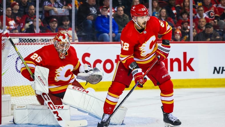 Mar 4, 2024; Calgary, Alberta, CAN; Calgary Flames defenseman MacKenzie Weegar (52) controls the puck in front of Calgary Flames goaltender Jacob Markstrom (25) during the first period against the Seattle Kraken at Scotiabank Saddledome. Mandatory Credit: Sergei Belski-USA TODAY Sports