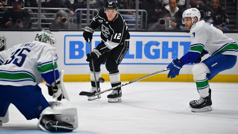 Mar 5, 2024; Los Angeles, California, USA; Los Angeles Kings left wing Trevor Moore (12) shoots on goal against Vancouver Canucks defenseman Carson Soucy (7) and goaltender Thatcher Demko (35) during the second period at Crypto.com Arena. Mandatory Credit: Gary A. Vasquez-USA TODAY Sports