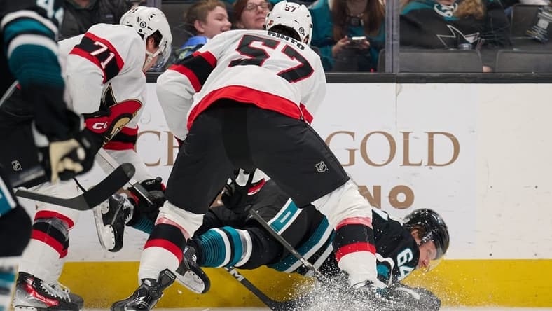 Mar 9, 2024; San Jose, California, USA: Ottawa Senators center Shane Pinto (57) and defenseman Nikolai Knyzhov (71) check San Jose Sharks center Mikael Granlund (64) to the ice during the first period at SAP Center at San Jose. Mandatory Credit: Robert Edwards-USA TODAY Sports