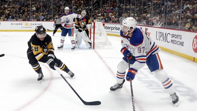 Mar 10, 2024; Pittsburgh, Pennsylvania, USA;  Edmonton Oilers center Connor McDavid (97) moves the puck against the Pittsburgh Penguins defenseman Kris Letang (58) during the second period at PPG Paints Arena. Mandatory Credit: Charles LeClaire-USA TODAY Sports