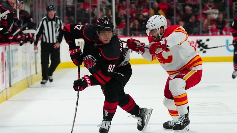 Mar 10, 2024; Raleigh, North Carolina, USA;  Carolina Hurricanes center Evgeny Kuznetsov (92) tries to control the puck against Calgary Flames right wing Matt Coronato (27) at PNC Arena. Mandatory Credit: James Guillory-USA TODAY Sports