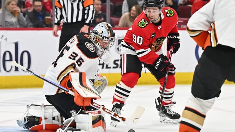 Mar 12, 2024; Chicago, Illinois, USA; Anaheim Ducks goaltender John Gibson (36) tracks a shot in the first period as Chicago Blackhawks forward Tyler Johnson (90) waits for the rebound at United Center. Mandatory Credit: Jamie Sabau-USA TODAY Sports