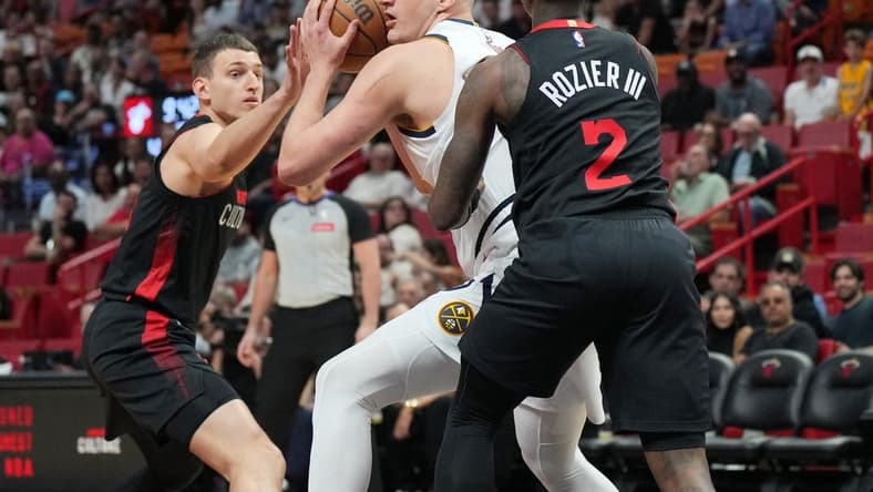 Mar 13, 2024; Miami, Florida, USA; Denver Nuggets center Nikola Jokic (15) drives to the basket as Miami Heat guard Terry Rozier (2) and Miami Heat forward Nikola Jovic (5), right, defend during the first half at Kaseya Center. Mandatory Credit: Jim Rassol-USA TODAY Sports