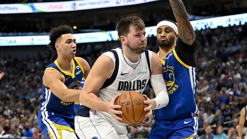 Mar 13, 2024; Dallas, Texas, USA; Dallas Mavericks guard Luka Doncic (77) drives to the basket past Golden State Warriors forward Trayce Jackson-Davis (32) and guard Gary Payton II (0) during the first half at the American Airlines Center. Mandatory Credit: Jerome Miron-USA TODAY Sports