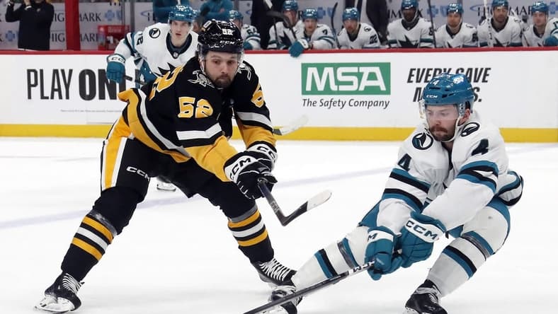 Mar 14, 2024; Pittsburgh, Pennsylvania, USA; San Jose Sharks defenseman Kyle Burroughs (4) defends Pittsburgh Penguins right wing Emil Bemstrom (52) during the first period at PPG Paints Arena. Mandatory Credit: Charles LeClaire-USA TODAY Sports