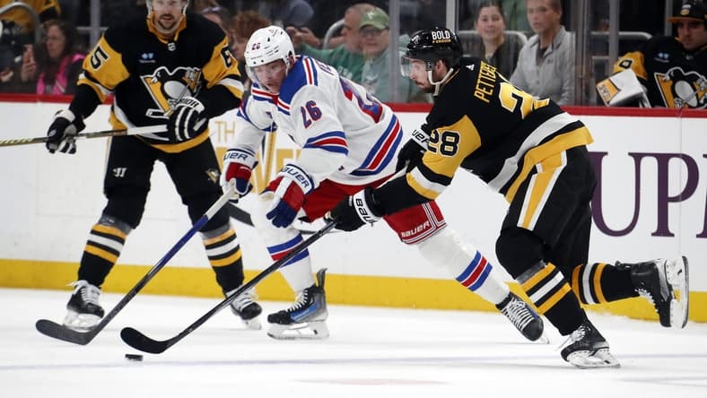 Mar 16, 2024; Pittsburgh, Pennsylvania, USA;  Pittsburgh Penguins defenseman Marcus Pettersson (28) moves the puck against New York Rangers left wing Jimmy Vesey (26) during the second period at PPG Paints Arena. Mandatory Credit: Charles LeClaire-USA TODAY Sports