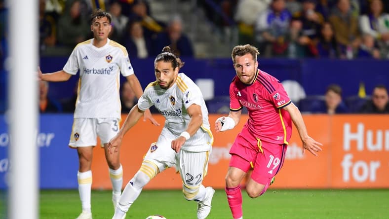 Mar 16, 2024; Carson, California, USA; LA Galaxy defender Martin Caceres (22) and St. Louis CITY SC midfielder Indiana Vassilev (19) chase down the ball during the first half at Dignity Health Sports Park. Mandatory Credit: Gary A. Vasquez-USA TODAY Sports