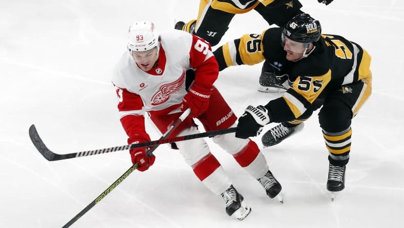 Mar 17, 2024; Pittsburgh, Pennsylvania, USA;  Detroit Red Wings right wing Alex DeBrincat (93) skates with he puck against Pittsburgh Penguins center Noel Acciari (55) during the third period at PPG Paints Arena. Pittsburgh won 6-3. Mandatory Credit: Charles LeClaire-USA TODAY Sports