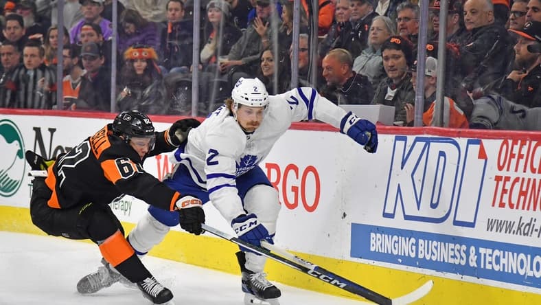 Mar 19, 2024; Philadelphia, Pennsylvania, USA; Toronto Maple Leafs defenseman Simon Benoit (2) and Philadelphia Flyers right wing Olle Lycksell (62) reach for the puck during the first period at Wells Fargo Center. Mandatory Credit: Eric Hartline-USA TODAY Sports