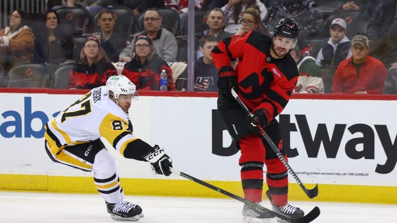 Mar 19, 2024; Newark, New Jersey, USA; New Jersey Devils defenseman Brendan Smith (2) passes the puck while being defended by Pittsburgh Penguins center Sidney Crosby (87) during the first period at Prudential Center. Mandatory Credit: Ed Mulholland-USA TODAY Sports