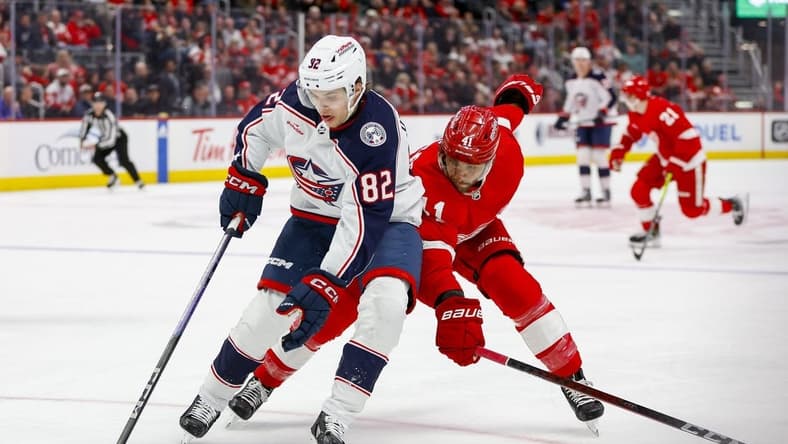 Mar 19, 2024; Detroit, Michigan, USA; Columbus Blue Jackets left wing Mikael Pyyhtia (82) handles the puck against Detroit Red Wings defenseman Shayne Gostisbehere (41) during the first period of the game against the Detroit Red Wings at Little Caesars Arena. Mandatory Credit: Brian Bradshaw Sevald-USA TODAY Sports