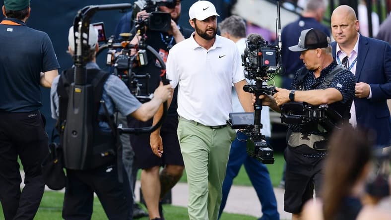 Scottie Scheffler is surrounded by cameras as he makes his way to the trophy riser after winning the tournament for the second year in a row at The Players Championship PGA golf tournament Sunday, March 17, 2024 at TPC Sawgrass in Ponte Vedra Beach, Fla.