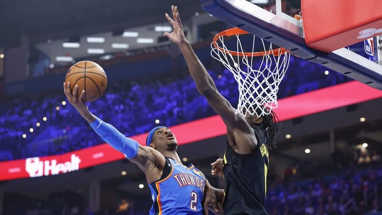 Mar 20, 2024; Oklahoma City, Oklahoma, USA; Oklahoma City Thunder guard Shai Gilgeous-Alexander (2) goes to the basket as Utah Jazz forward Taylor Hendricks (0) defends during the second quarter at Paycom Center. Mandatory Credit: Alonzo Adams-USA TODAY Sports