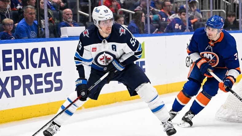 Mar 23, 2024; Elmont, New York, USA;  Winnipeg Jets center Mark Scheifele (55) skates with the puck chased by New York Islanders defenseman Adam Pelech (3) during the third period at UBS Arena. Mandatory Credit: Dennis Schneidler-USA TODAY Sports