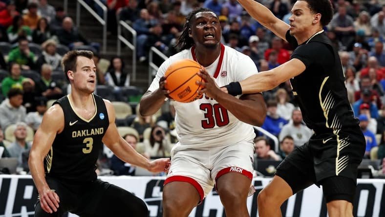 Mar 23, 2024; Pittsburgh, PA, USA; North Carolina State Wolfpack forward DJ Burns Jr. (30) drives to the basket against Oakland Golden Grizzlies forward Chris Conway (2) and guard Jack Gohlke (3) during the second half in the second round of the 2024 NCAA Tournament at PPG Paints Arena. Mandatory Credit: Charles LeClaire-USA TODAY Sports
