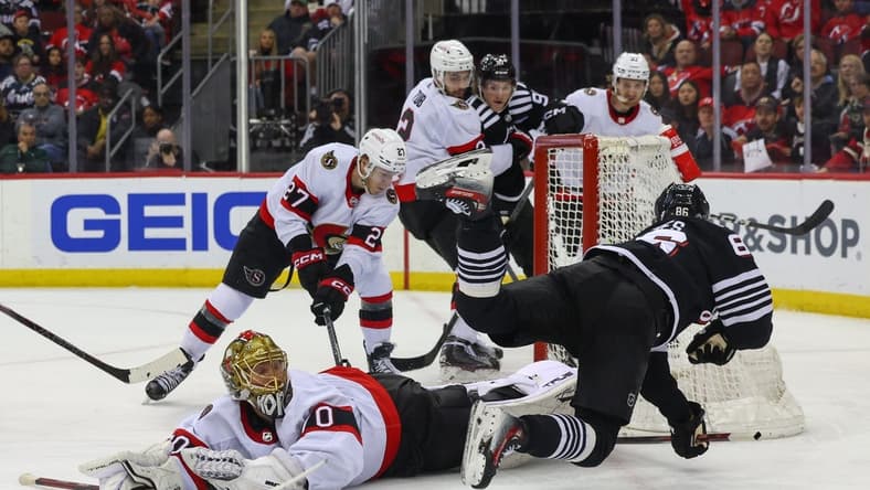 Mar 23, 2024; Newark, New Jersey, USA; Ottawa Senators goaltender Joonas Korpisalo (70) makes a save on New Jersey Devils center Jack Hughes (86) during the second period at Prudential Center. Mandatory Credit: Ed Mulholland-USA TODAY Sports