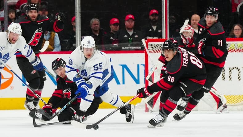 Mar 24, 2024; Raleigh, North Carolina, USA;  Carolina Hurricanes defenseman Brett Pesce (22) and left wing Teuvo Teravainen (86) battle Toronto Maple Leafs left wing Tyler Bertuzzi (59) for the puck during the first period at PNC Arena. Mandatory Credit: James Guillory-USA TODAY Sports