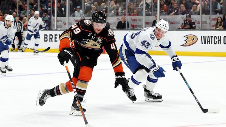 Mar 24, 2024; Anaheim, California, USA; Anaheim Ducks left wing Max Jones (49) keeps the puck from Tampa Bay Lightning defenseman Darren Raddysh (43) during the second period at Honda Center. Mandatory Credit: Jason Parkhurst-USA TODAY Sports