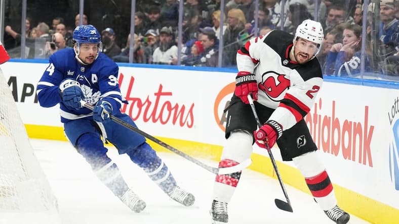 Mar 26, 2024; Toronto, Ontario, CAN; Toronto Maple Leafs center Auston Matthews (34) battles for the puck with New Jersey Devils defenseman Brendan Smith (2) during the first period at Scotiabank Arena. Mandatory Credit: Nick Turchiaro-USA TODAY Sports