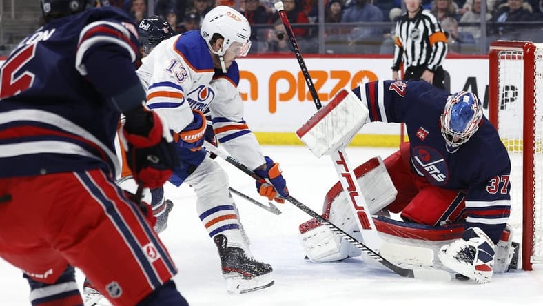 Mar 26, 2024; Winnipeg, Manitoba, CAN; Winnipeg Jets goaltender Connor Hellebuyck (37) covers up a rebound from Edmonton Oilers center Mattias Janmark (13) in the first period at Canada Life Centre. Mandatory Credit: James Carey Lauder-USA TODAY Sports