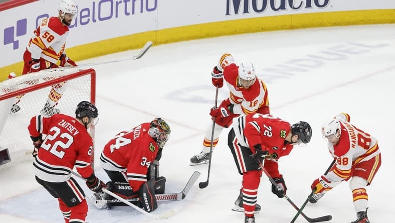 Mar 26, 2024; Chicago, Illinois, USA; Chicago Blackhawks defenseman Alex Vlasic (72) battles for the puck with Calgary Flames left wing Andrew Mangiapane (88) during the second period at United Center. Mandatory Credit: Kamil Krzaczynski-USA TODAY Sports