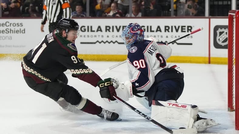 Mar 26, 2024; Tempe, Arizona, USA; Columbus Blue Jackets goaltender Elvis Merzlikins (90) makes the save on Arizona Coyotes right wing Josh Doan (91) in the second period at Mullett Arena. Mandatory Credit: Rick Scuteri-USA TODAY Sports
