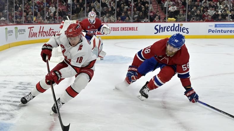 Mar 30, 2024; Montreal, Quebec, CAN; Carolina Hurricanes forward Jack Drury (18) plays the puck and Montreal Canadiens defenseman David Savard (58) defends during the first period at the Bell Centre. Mandatory Credit: Eric Bolte-USA TODAY Sports