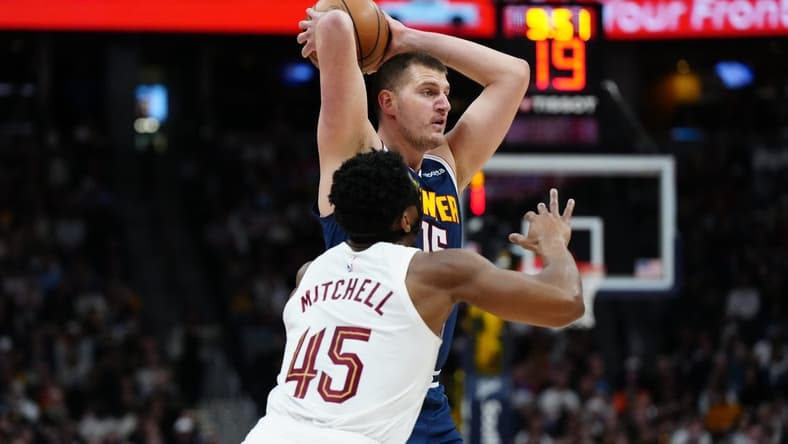 Mar 31, 2024; Denver, Colorado, USA; Denver Nuggets center Nikola Jokic (15) prepares to pass the ball over Cleveland Cavaliers guard Donovan Mitchell (45) in the first quarter at Ball Arena. Mandatory Credit: Ron Chenoy-USA TODAY Sports