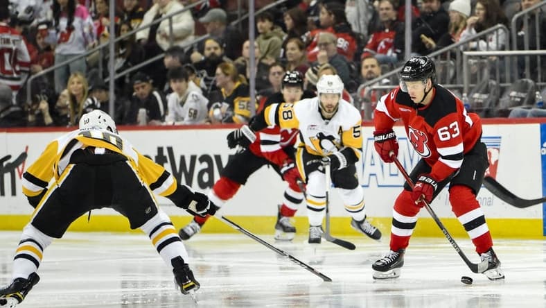 Apr 2, 2024; Newark, New Jersey, USA; New Jersey Devils left wing Jesper Bratt (63) skates with the puck while being defended by Pittsburgh Penguins left wing Drew O'Connor (10) and Pittsburgh Penguins defenseman Ryan Shea (5) during the second period at Prudential Center. Mandatory Credit: John Jones-USA TODAY Sports