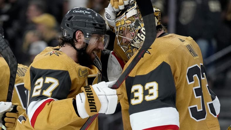 Vegas Golden Knights defenseman Shea Theodore (27) celebrates with goaltender Adin Hill (33) after Game 1 of the NHL hockey Stanley Cup Final against the Florida Panthers, Saturday, June 3, 2023