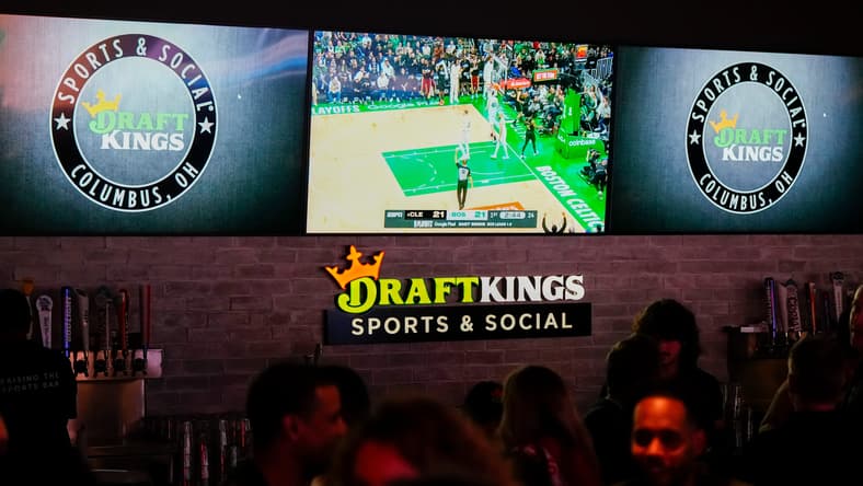 Sports are shown on TVs behind a bar as guests enjoy the grand opening of DraftKings Sports & Social in Ohio.
