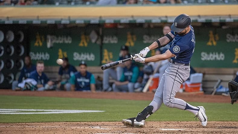 Jun 21, 2022; Oakland, California, USA; Seattle Mariners right fielder Jesse Winker (27) hits an rbi single during the fifth inning against the Oakland Athletics at RingCentral Coliseum. Mandatory Credit: Ed Szczepanski-USA TODAY Sports